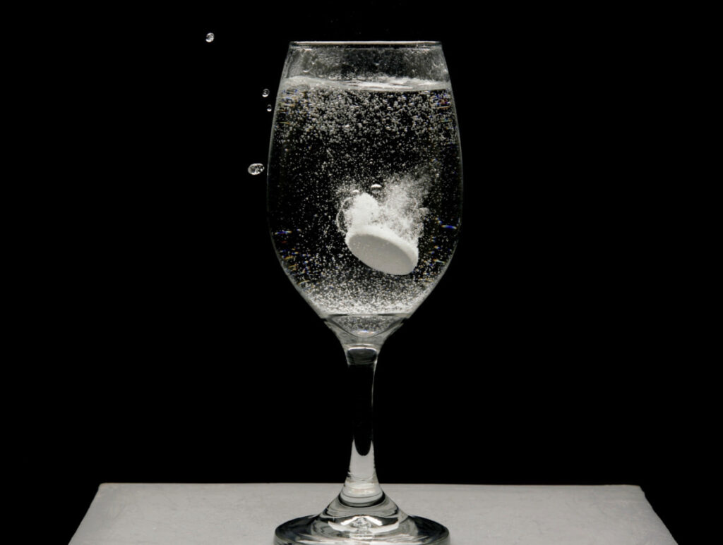 alka seltzer dropped in a water inside a wine glass