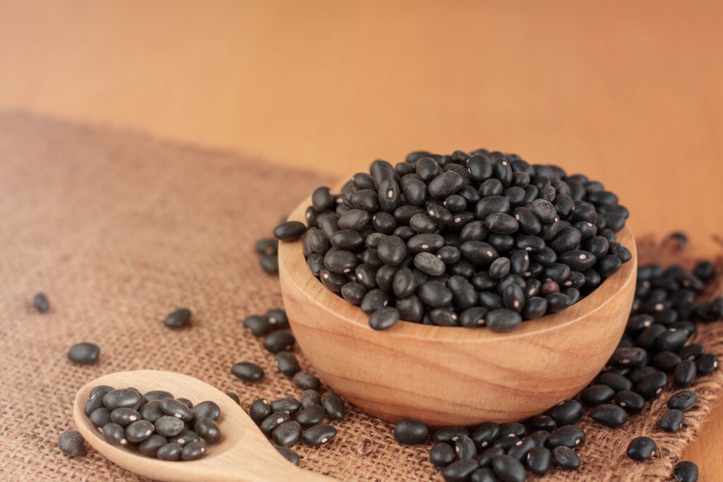 black beans on a wooden bowl and wooden spoon beside