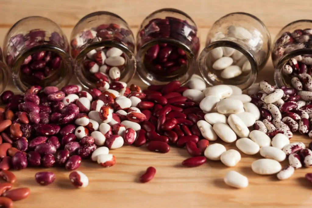 different types of beans scattered on top of a wooden table