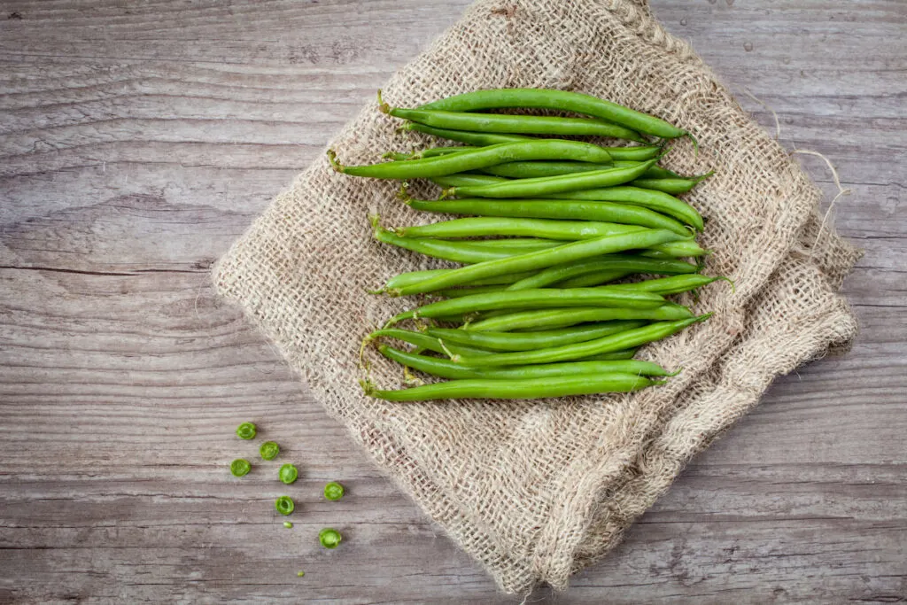 green beans on a cloth on top of a wooden table 