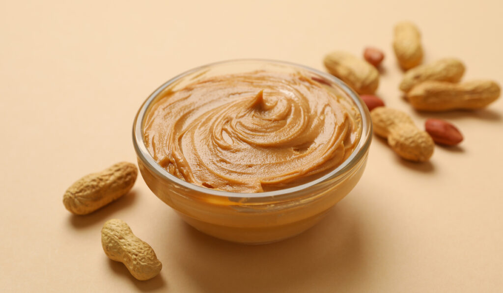 a peanut butter in a bowl with whole peanuts on the side