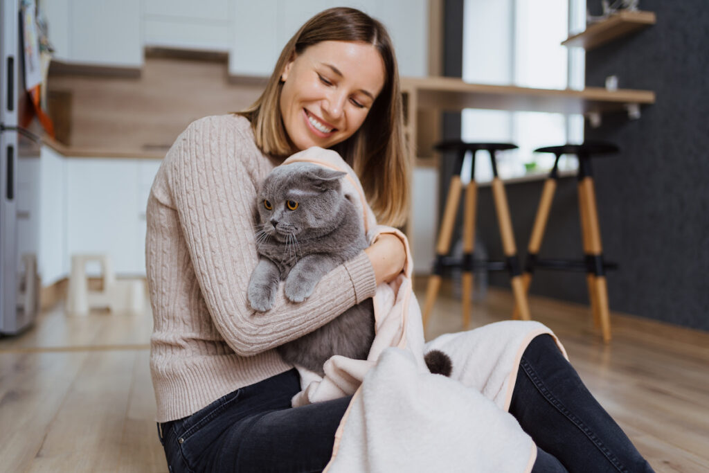 a gray cat on its owners arms in the kitchen space