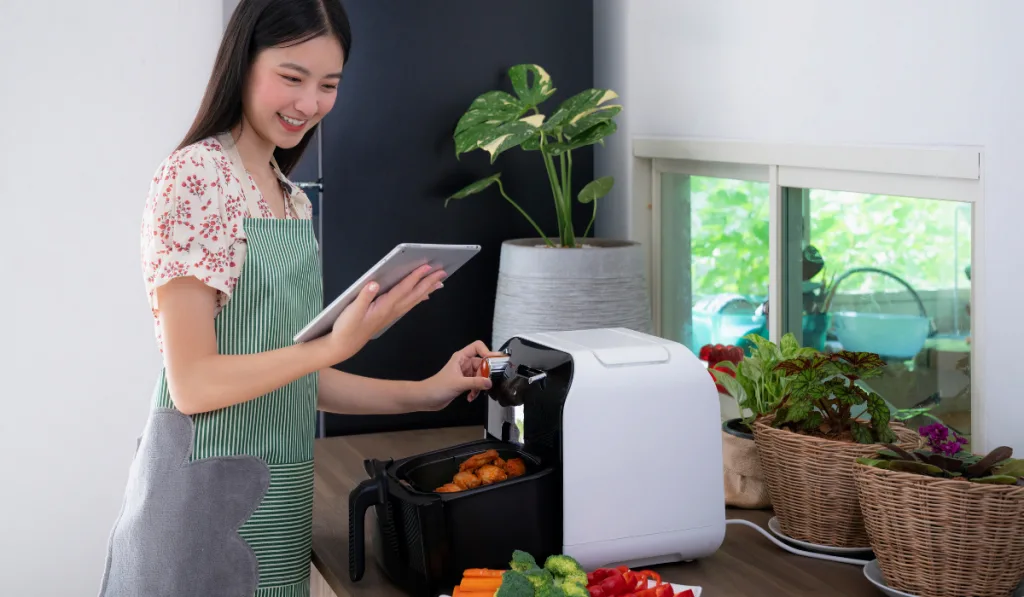 A girl cooking using the air fryer in the kitchen.