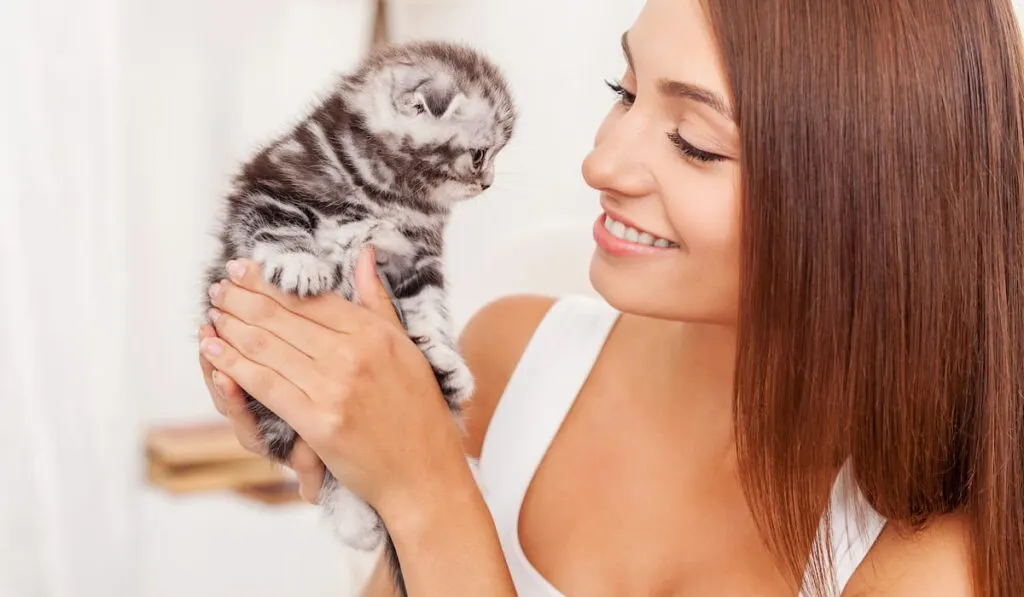 young woman holding little kitten