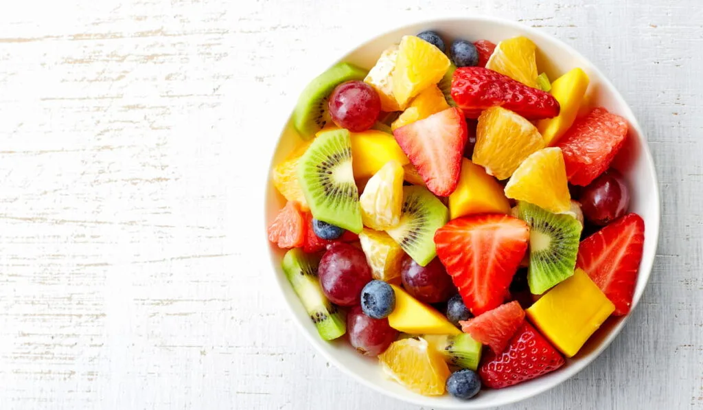 Bowl of healthy fresh fruit salad on wooden background 