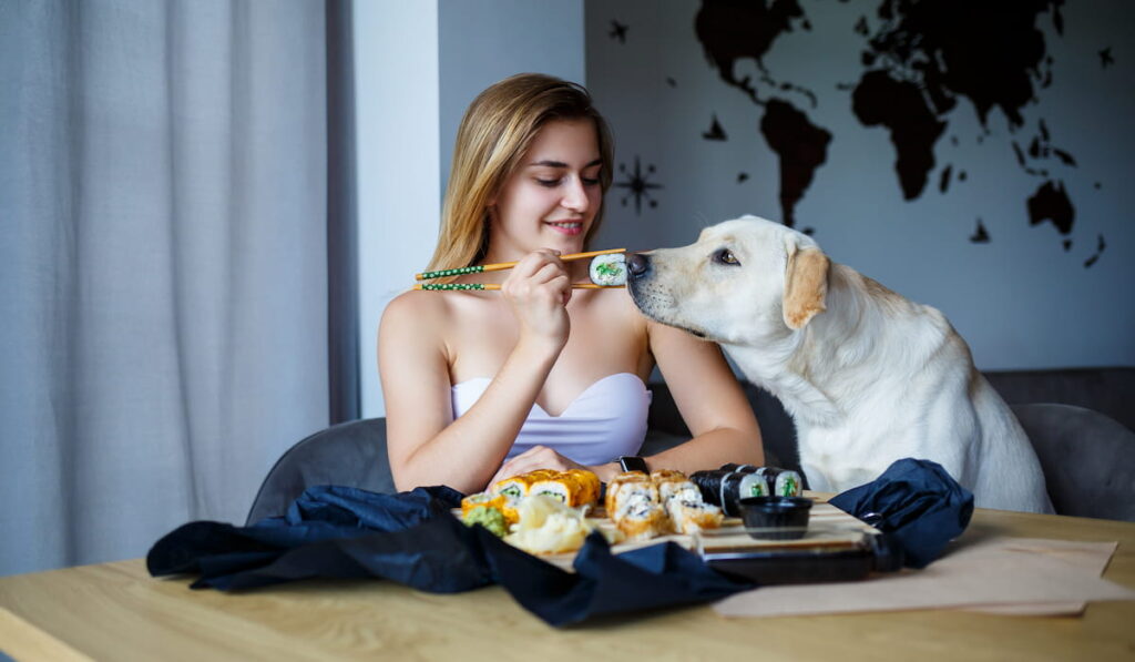 woman eating sushi with her dog 