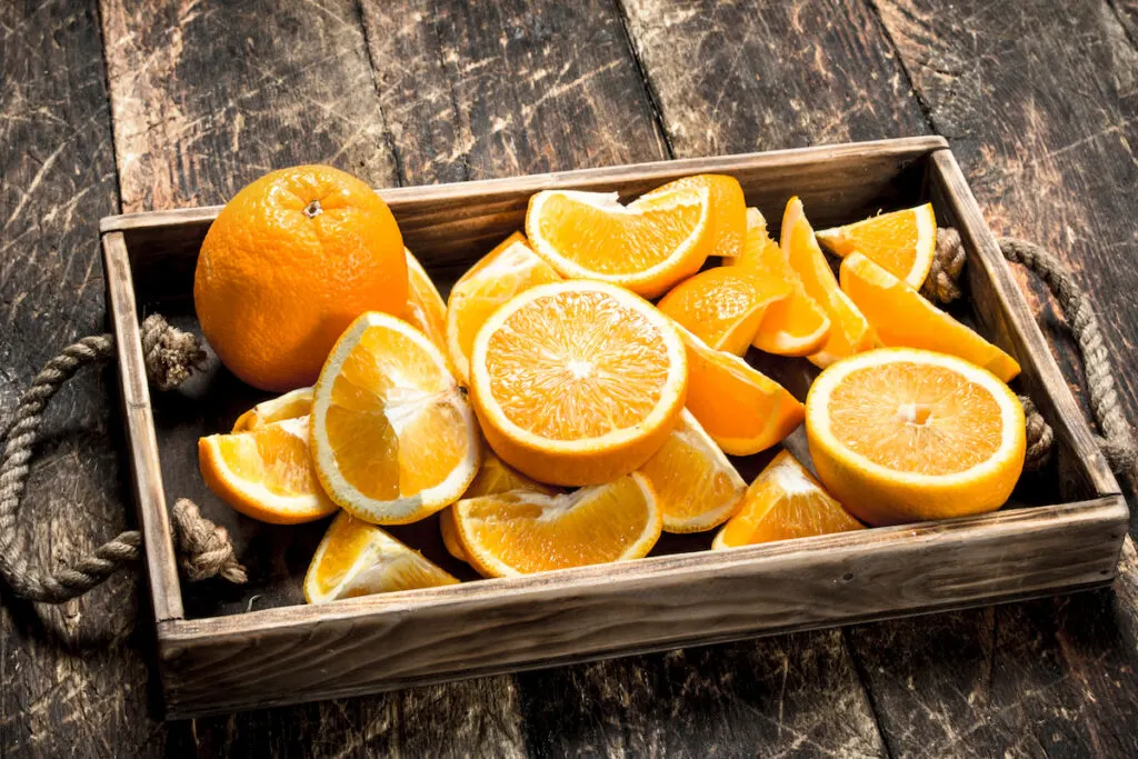 Fresh oranges on a wooden tray on rustic background